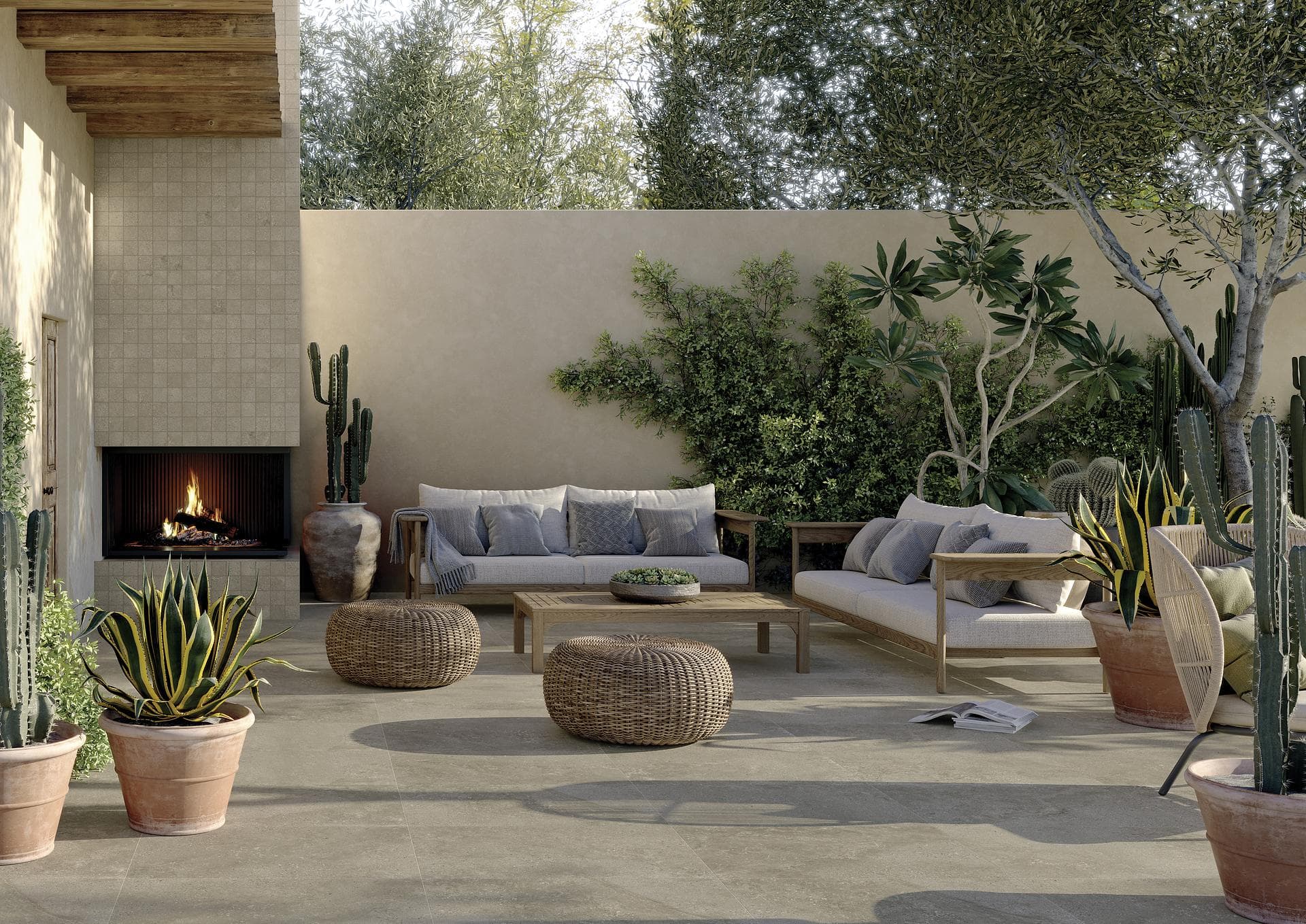 Patio extérieur avec cheminée et sol effet pierre Patio avec cheminée allumée, canapés et poufs en rotin sur sol effet pierre beige foncé et mosaïque