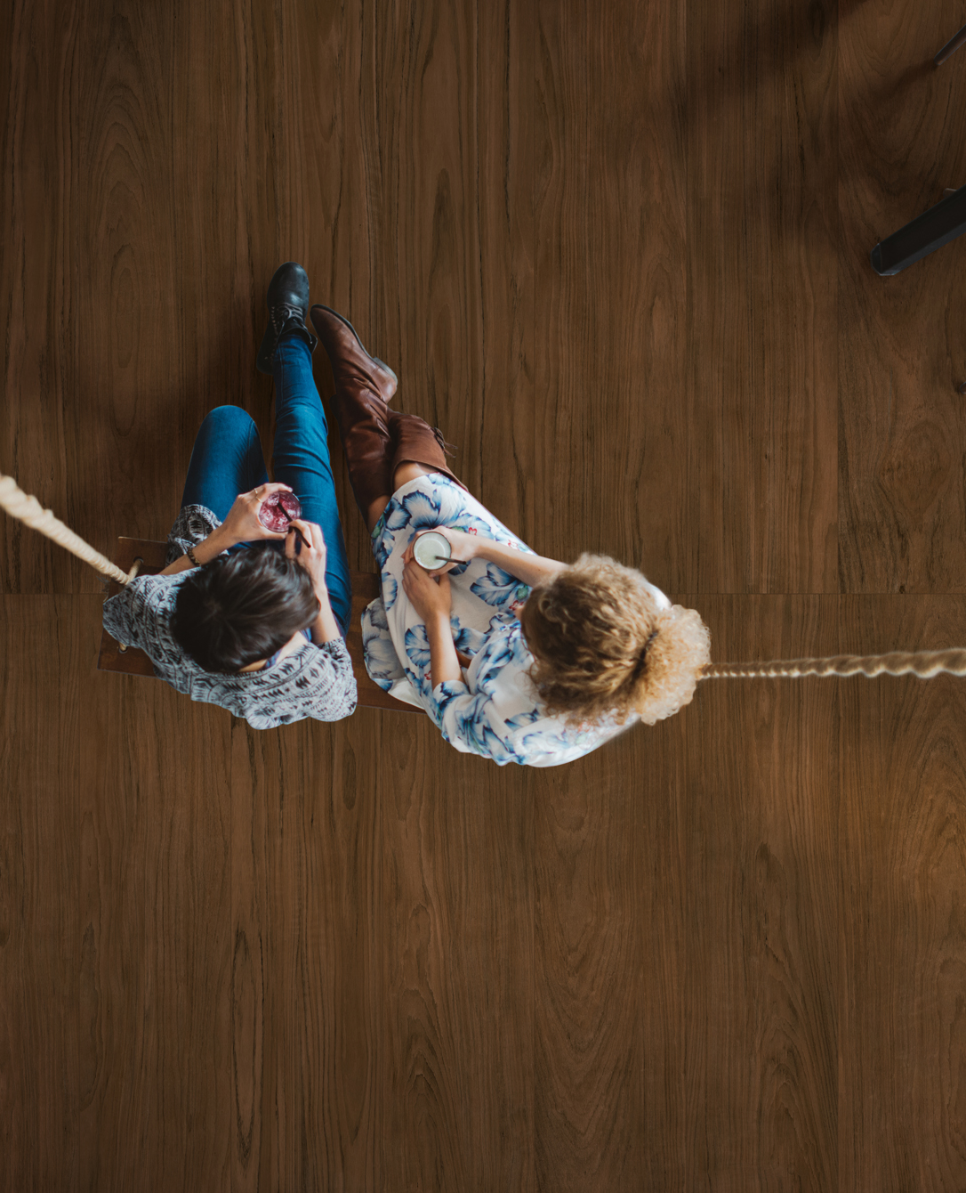 Two Friends Sitting On A Swing At The Restaurant